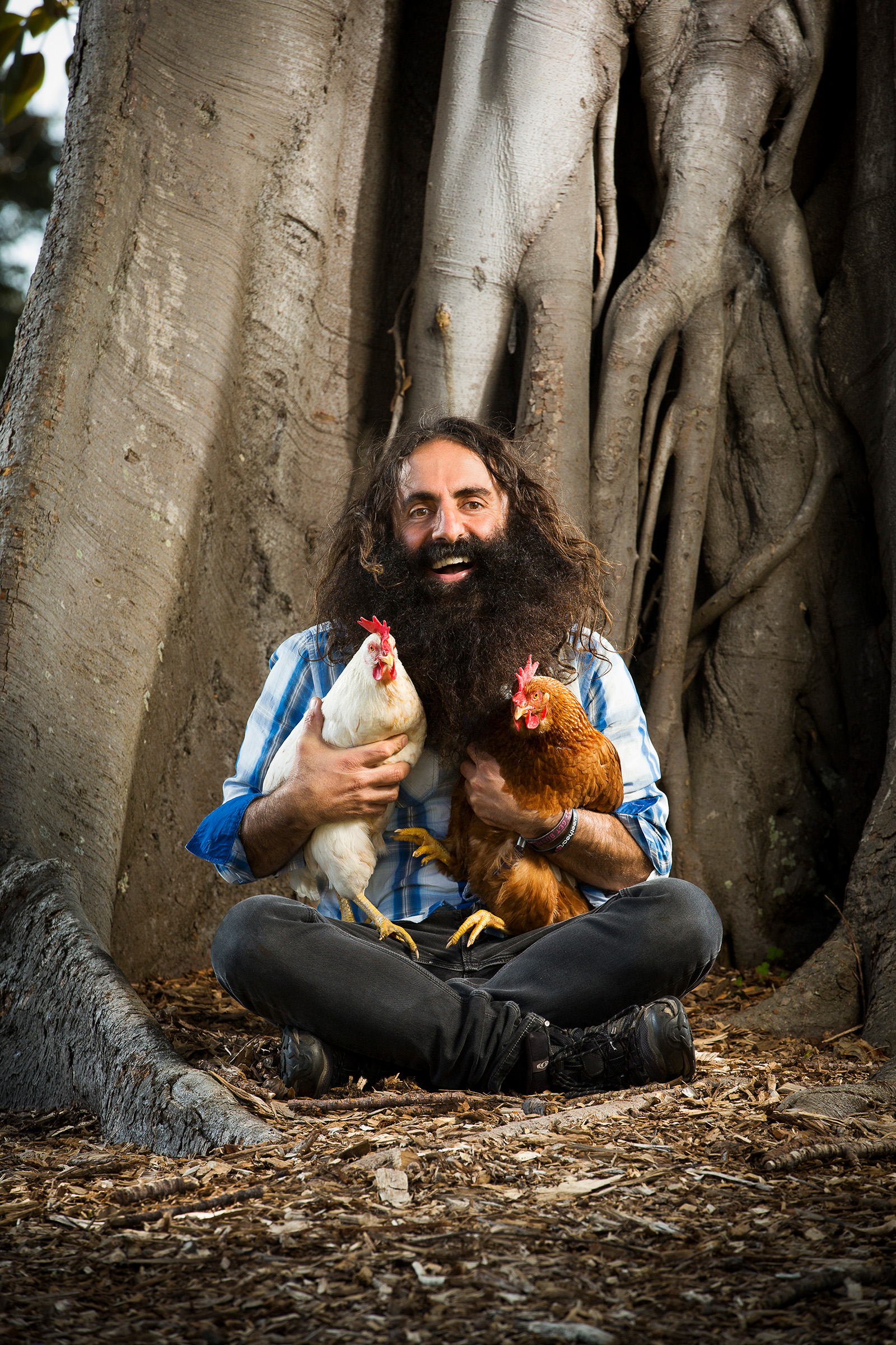 Editorial location photography Costa Georgiadis Gardening Australia sitting by tree holding red and white chicken